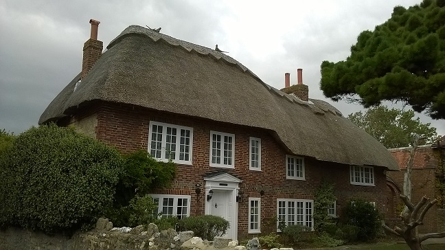Homestead House is a red brick thatch cottage with white framed windows and front door. The front garden is exceptionally well maintained.