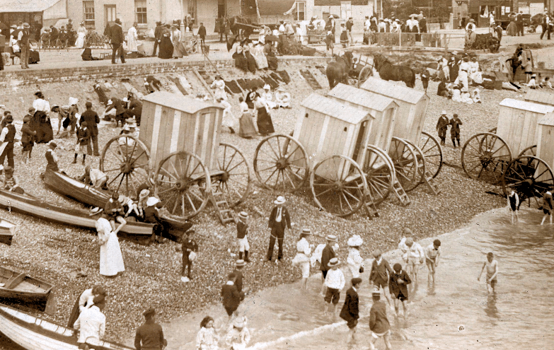 People paddling in the sea alongside bathing machines