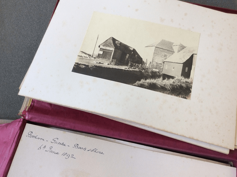 Photograph showing a sepia image from PH 26113. The photograph is mounted on stained cream card. Written on the back of a second photograph is written below stating Bosham, Sussex, Boats and Shore 6th June 1892.