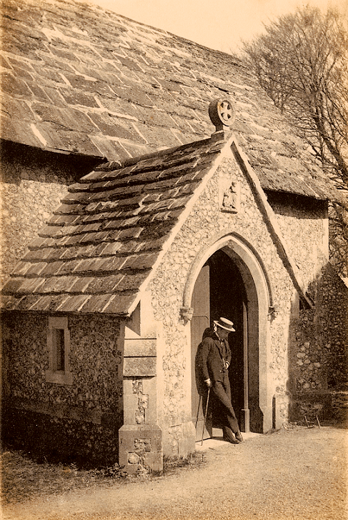 Sepia image of the south entrance to the church. A well-dressed man leans against the door.