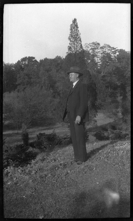Black and white full body portrait of Wilson in a three piece suit and fedora hat.