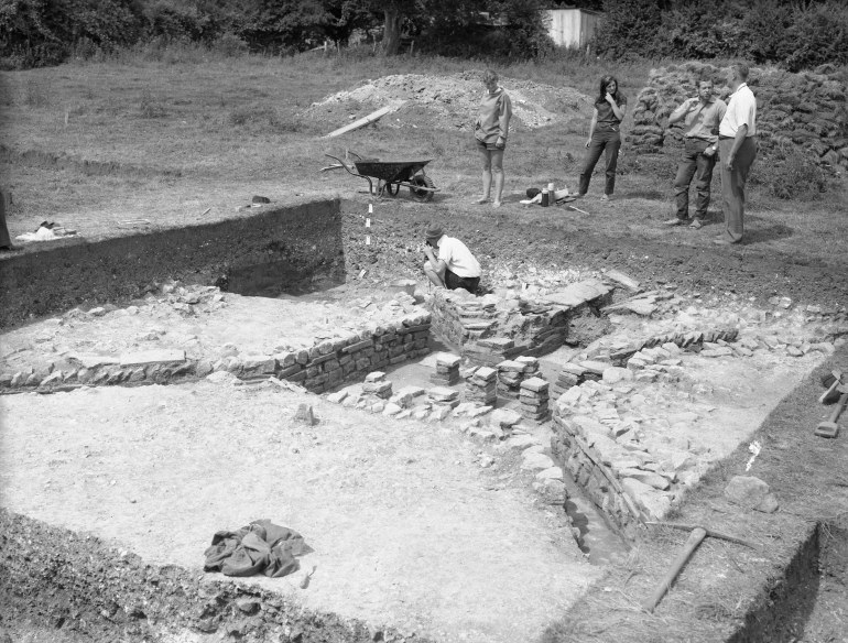 Five archaeologists working and talking at the dig.