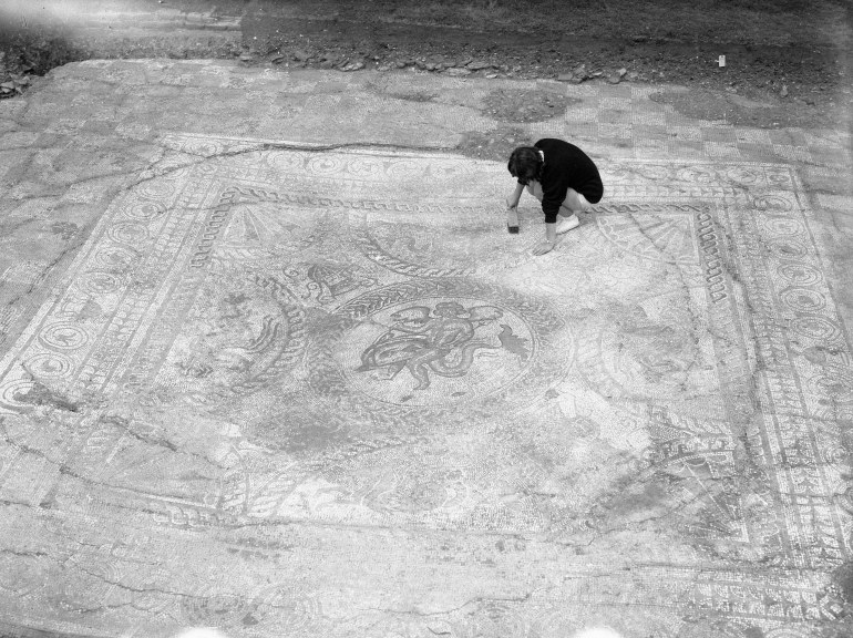 Archaeologist brushing clean the large Roman tiled floor.