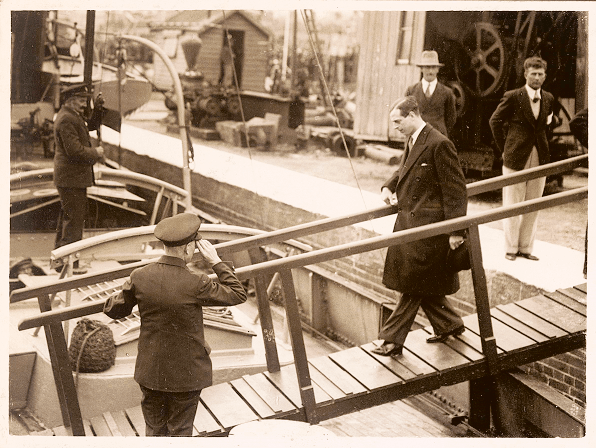 Prince George is walking down a ramp to mount a boat.