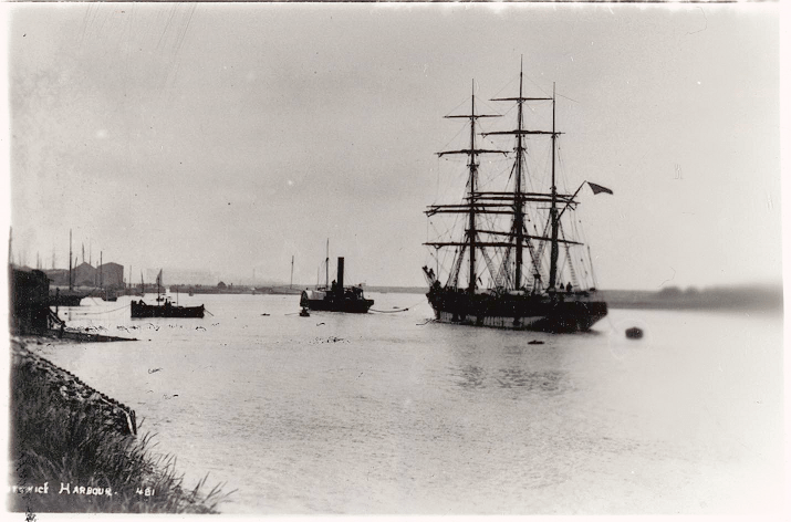 A large rig sailing ship is making its way along the harbour