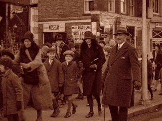 Sepia film of mothers taking their children to a showing at the cinema. The fashion is typical of the 1920s