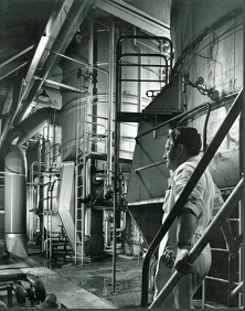 Man standing on metal stairs next to large metal tankards