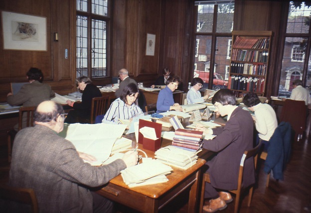 Researchers surrounded by books and documents, each table is in use by a researcher (10 in total)