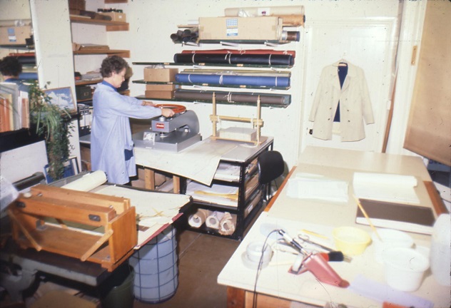 Shows equipment and documents in the process of being repaired, with a Conservator using a small press