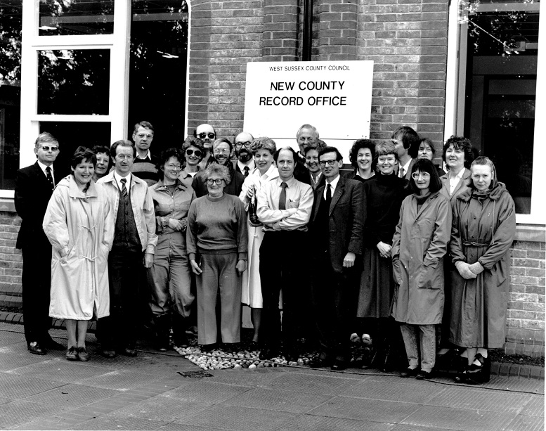 Black and white photograph, a large sign behind the staff reads 'West Sussex County Council, New County Record Office)