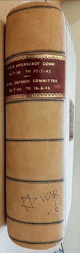 On the spine of the ARP Emergency Committee Minutes for WWII, a leather and fabric bound book, is a pen drawing of the star of David, and the word WAR in all capitals.
