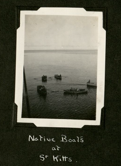 Black and white portrait photograph of small wooden paddling boats - five in total - in the water at St. Kitts
