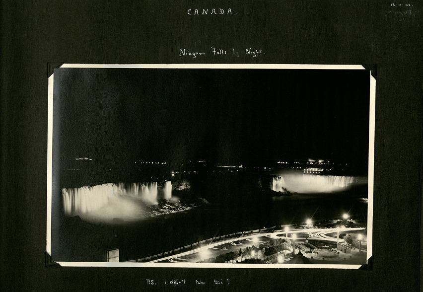 Black and white photograph taken at night of niagra falls. The two waterfalls are lit up, as is the grounds opposite.