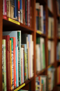 Colour photograph showing books on a dark wooden shelf. The photos blurs out of focus beyond the first shelf.